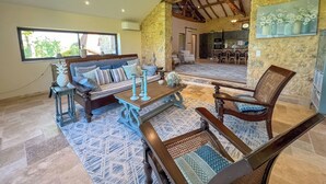 Ein geräumiger Wohnbereich mit Sofa, Esstisch und Stuhl. Im Hintergrund ist eine Küche erkennbar.