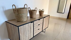 Ein Holzschrank mit drei gewebten Körben obenauf, Schubladen und einem Fliesenboden.