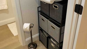 A compact bathroom with a toilet, a towel rack, and a storage unit with drawers.