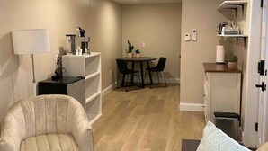 A compact living space with a sofa, a chair, a small table, and a dining area with chairs.