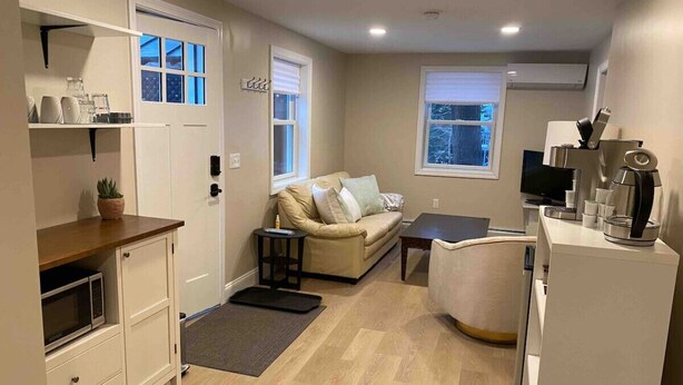 A compact living space with a kitchenette, a sofa, a coffee machine, and a TV.
