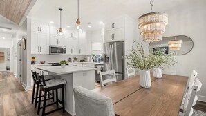 A modern kitchen with white cabinets, stainless steel appliances, and a central island. - Coastal Retreat by Golf & Water; Screened Porch (Townsend)
