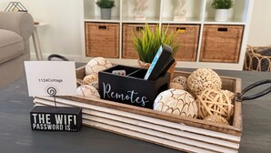 A wooden tray with a sign reading "Remotes" and a sign indicating "The WiFi password is...". - Coastal Retreat by Golf & Water; Screened Porch (Townsend)