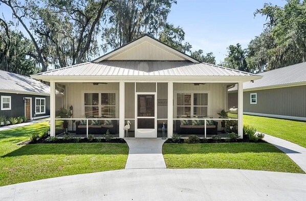A two-story house with a covered porch, a front door, and a small garden area.