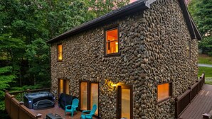 A stone house with a deck, outdoor seating, and a hot tub. - Stone-Built Cabin w/ Indoor Pool, Firepit, & Bunk Room @ Smokies Retreat! (Sevierville)