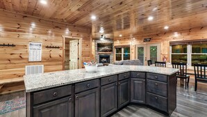 A modern kitchen with dark cabinets, granite countertops, and a built-in island. - Log Cabin Retreat in the Smoky Mountain:Private Hot Tub, Billiards, Arcade Games (Gatlinburg)