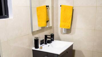 Un baño con un lavamanos blanco, un mueble negro y una toalla amarilla colgada en la pared.
