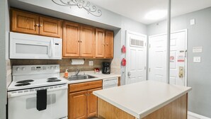 Una cocina con armarios de madera, estufa blanca, microondas y cafetera.