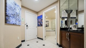 A hotel corridor with a tiled floor, a white door, a bathroom with a sink and mirror, and a kitchen area with stainless steel appliances. - PH Floor Studio • Strip View • Balcony • No Resort Fee D30O3 (Las Vegas)