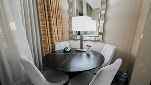 A hotel room with a round table, four chairs, a telephone, a lamp, and a mirror. - PH Floor Studio • Strip View • Balcony • No Resort Fee D30O3 (Las Vegas)