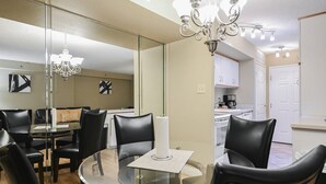 Zona pranzo moderna con tavolo in vetro, sedie nere e lampadario.