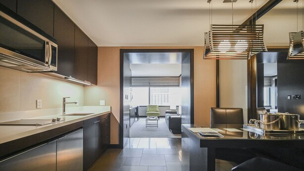 A modern kitchen with stainless steel appliances, a dining area with a glass table, and a view to a living space. - Vdara Studio • City View • Free Valet • Pool • L20 (Las Vegas)