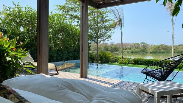 Un espace aménagé au bord de la piscine, avec un lit, des chaises longues et une vue sur un lac.