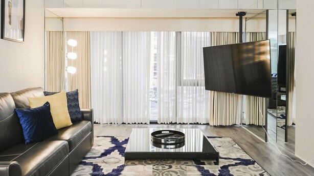 A modern living room with a leather sofa, patterned rug, and a large flat-screen TV.