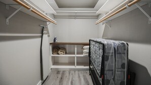 A compact utility room with a wooden bench, shelves, and a mattress on wheels.
