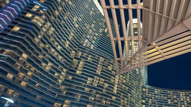 Un hotel moderno de gran altura, con un diseño distintivo que incluye una fachada inclinada y una estructura abierta y espaciosa con un patrón de cuadrícula.