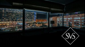 Una habitación de hotel moderna con amplios ventanales de piso a techo que ofrecen vistas nocturnas de la ciudad.