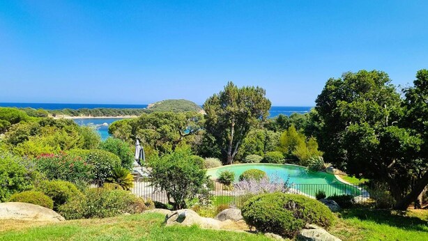Un área ajardinada con piscina, una estatua y vistas al mar.