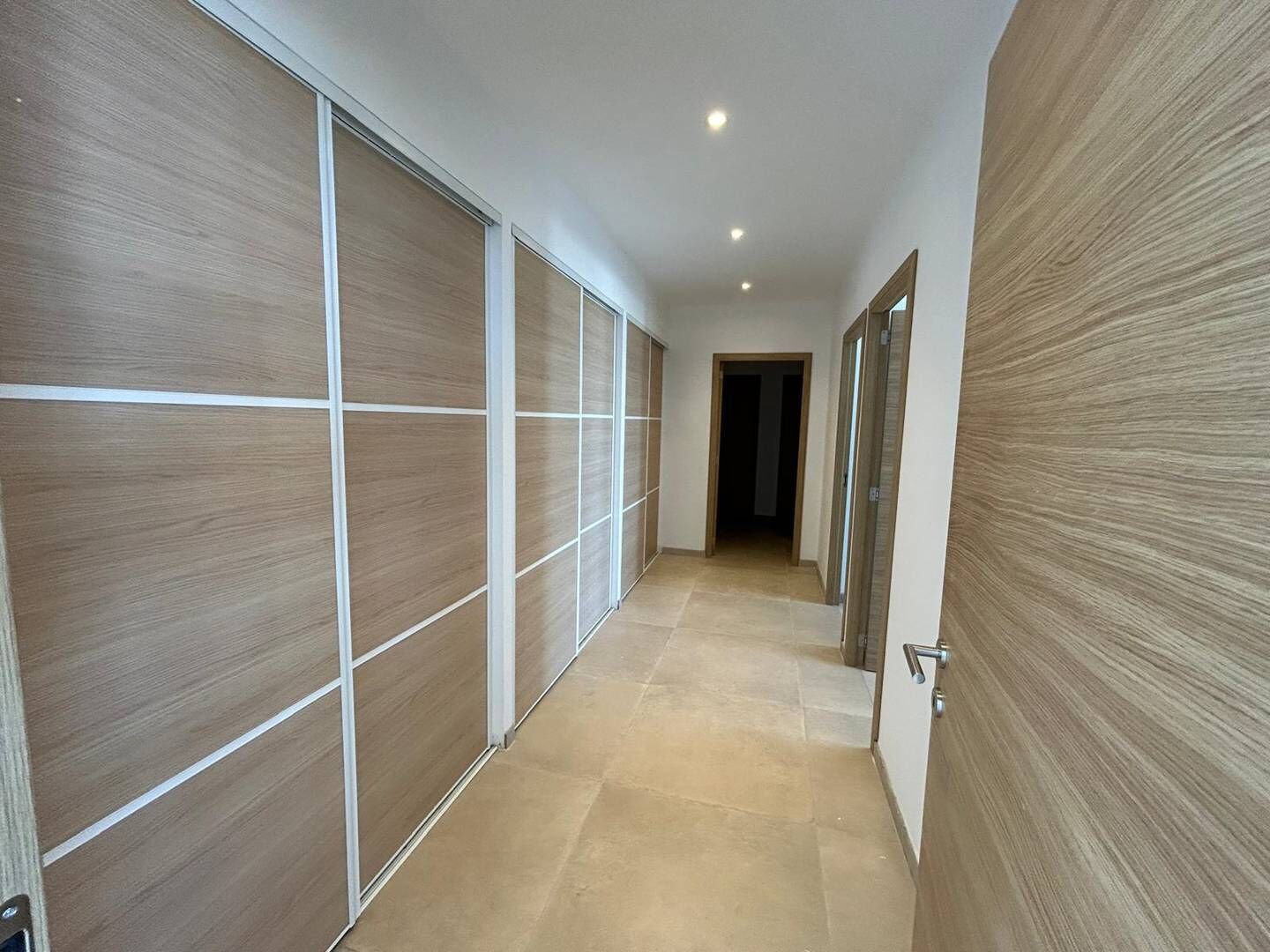 A hallway with sliding doors and a tiled floor.