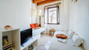 Una habitación pequeña con cama, televisión, estantería y ventana con vistas al exterior.