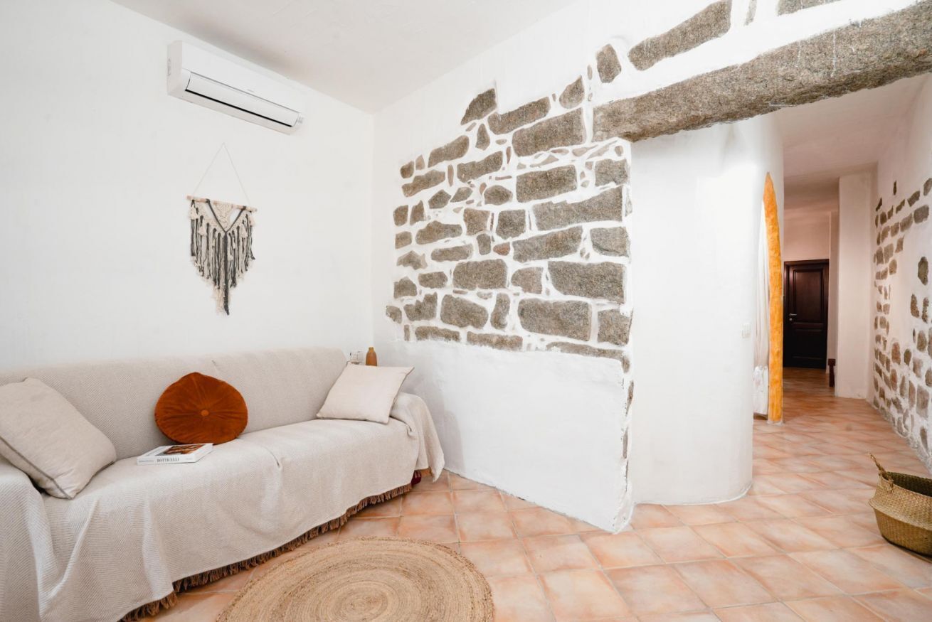 Um quarto acolhedor com parede de pedra, um sofá branco e um tapete tecido.