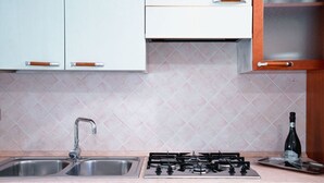 A kitchen with two sinks, a gas stove, and a bottle of wine on the counter. - San Teodoro, Martino House (San Teodoro)