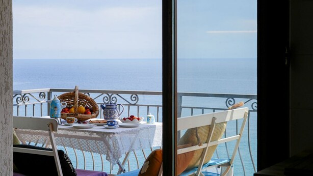 Un balcon avec une table préparée pour le petit-déjeuner, donnant sur la mer.