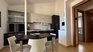 Eine moderne Küche mit Essbereich, mit einem dunklen Holztisch, weißen Stühlen und einem eingebauten Backofen.