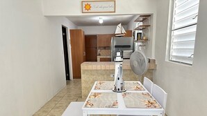 A small kitchen with a dining table and chairs, a fan, and a decorative sailboat model. - Sunny Flamboyan Boqueron, 3 bdr/2 bath house w/pool, sleeps 11 (Cabo Rojo)