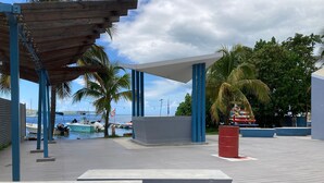 A waterfront promenade with a covered seating area, palm trees, and boats docked in the background. - Sunny Flamboyan Boqueron, 3 bdr/2 bath house w/pool, sleeps 11 (Cabo Rojo)