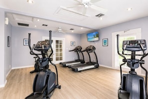 Een sportschool thuis met loopbanden, een elliptische trainer en een hometrainer.