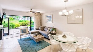 En moderne stue med sofa, sofabord og spiseområde med stole.