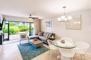 Ein modernes Wohnzimmer mit Sofa, Couchtisch und Essbereich mit Stühlen.