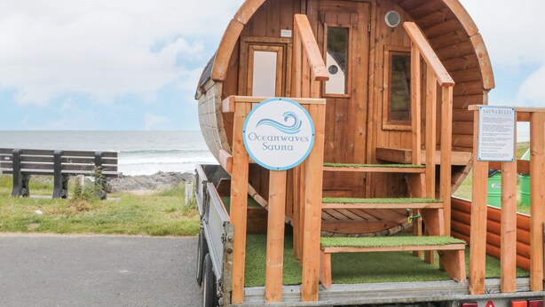 En træhytte med et skilt, der viser "Oceanwaves Sauna", og et skilt, der angiver saunaens regler.