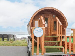 Eine Holzhütte mit einem Schild, auf dem "Oceanwaves Sauna" steht, und einem Schild mit Sauna-Regeln.