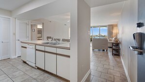 A modern kitchen with a central island, a dining area with a sofa and table, and a view of the outdoors.