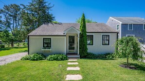A single-story house with a front porch, a small garden, and a clear sky.