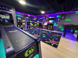 A gaming arcade with various arcade machines, a neon-lit floor, and a 'Roll and Score' game.