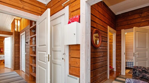 Een houten interieur met een witte deur, een spiegel en een geruit tapijt.