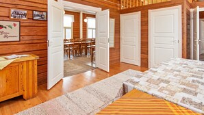 Een houten interieur met een eethoek, twee deuren en een bed.