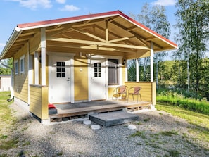 Eine kleine Holzhütte mit einer Veranda, zwei Türen und einer Sitzecke mit zwei Stühlen.