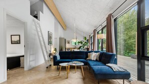 Un soggiorno moderno con un divano modulare blu, un tavolino rotondo e un pavimento in legno a parquet a spina di pesce.