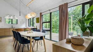 Una cucina moderna con zona pranzo, ampie finestre e vista su un'area verde.