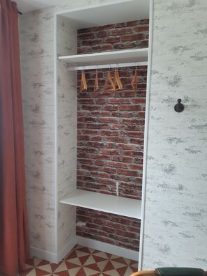 A room with a brick wall, white shelves, and a red curtain. - La Maison-Gîte-Family-Ensuite with Shower-Garden view (Beaulieu-sur-Layon)