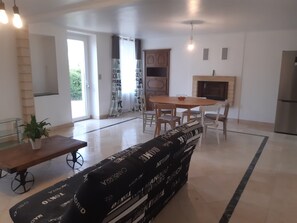 Un salon moderne comprenant un canapé, une table à manger avec des chaises, une cheminée et un coin cuisine.
