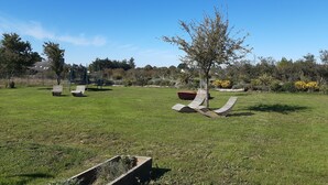 A grassy outdoor area with a tree, two lounge chairs, and a swing set. - La Maison-Gîte-Family-Ensuite with Shower-Garden view (Beaulieu-sur-Layon)