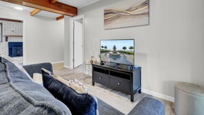 En stue med et mørkt træunderholdningscenter, et stort fladskærms-tv og en grå modulsofa.