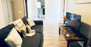 A living room with a sofa, a coffee table, and a television. - Charleston Cozy Apartment - Near Airport & Plantations / Free Parking (Ladson)