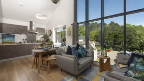 Una cocina moderna con comedor, ventanas amplias y vistas al bosque.