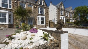 A stone house with a garden featuring white pebbles, purple flowers, and a lion statue.